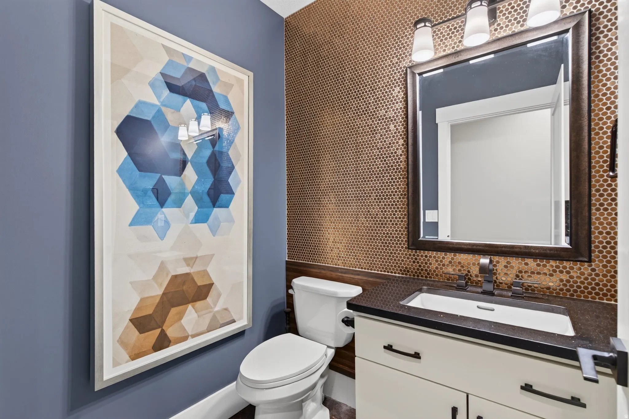 Vanity with white shaker cabinetry, dark countertop, and integrated sink