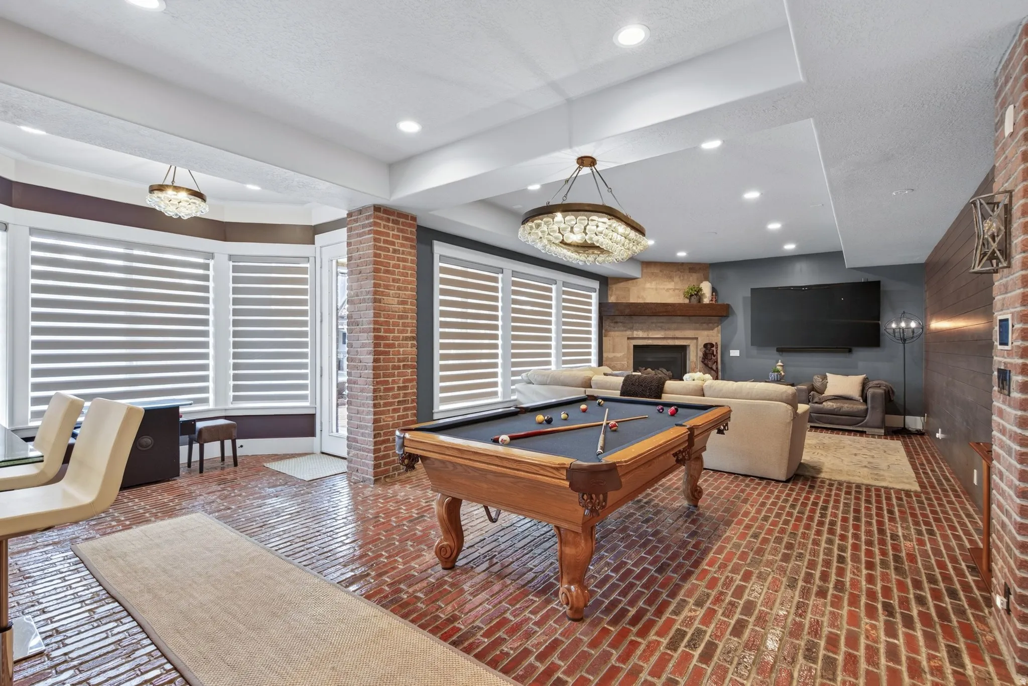 Brick flooring, bay windows with blinds, recessed lighting, fireplace with mantel, and a built-in television mount