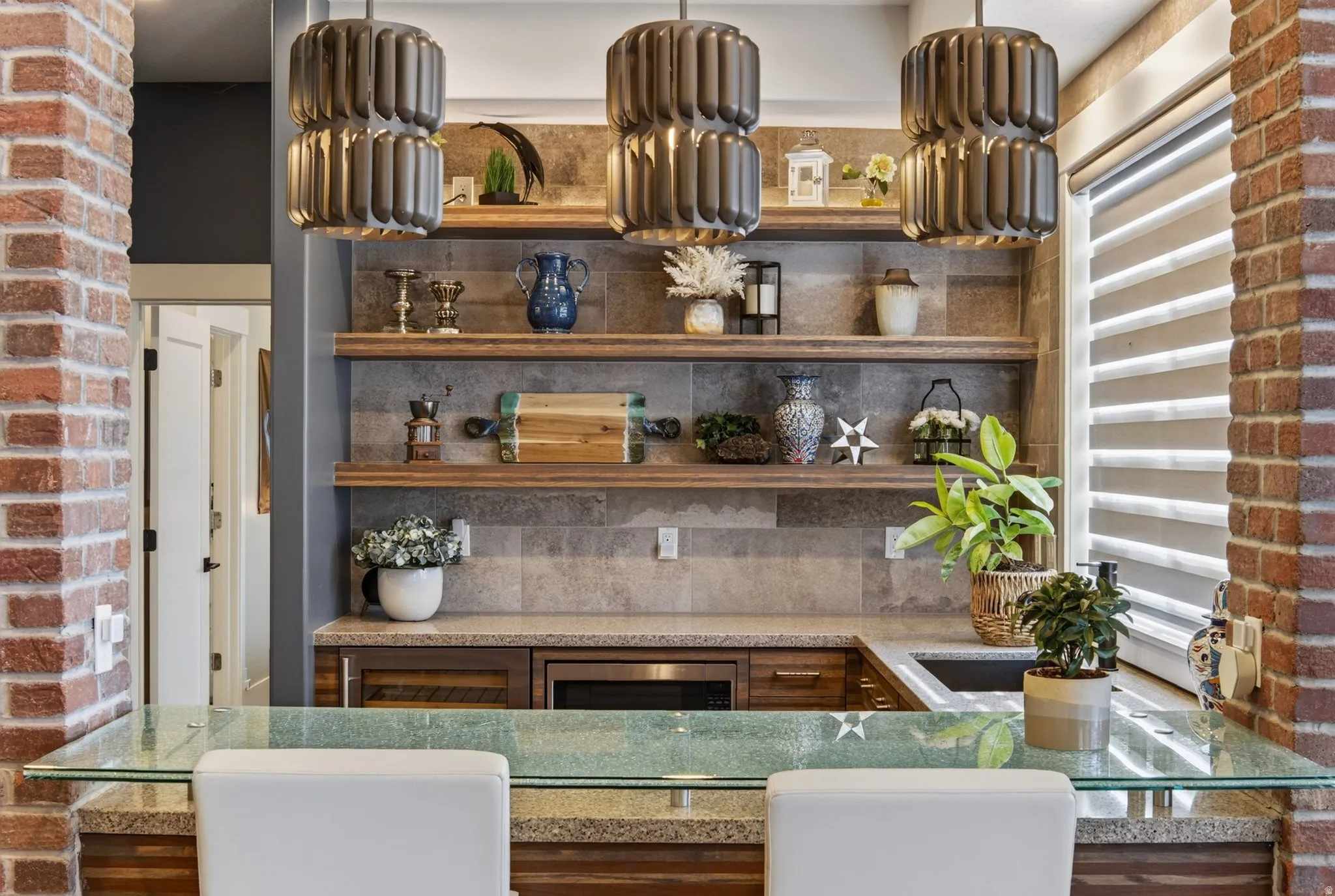 Built-in wet bar featuring a glass countertop, integrated microwave, beverage refrigerator, and open wood shelving