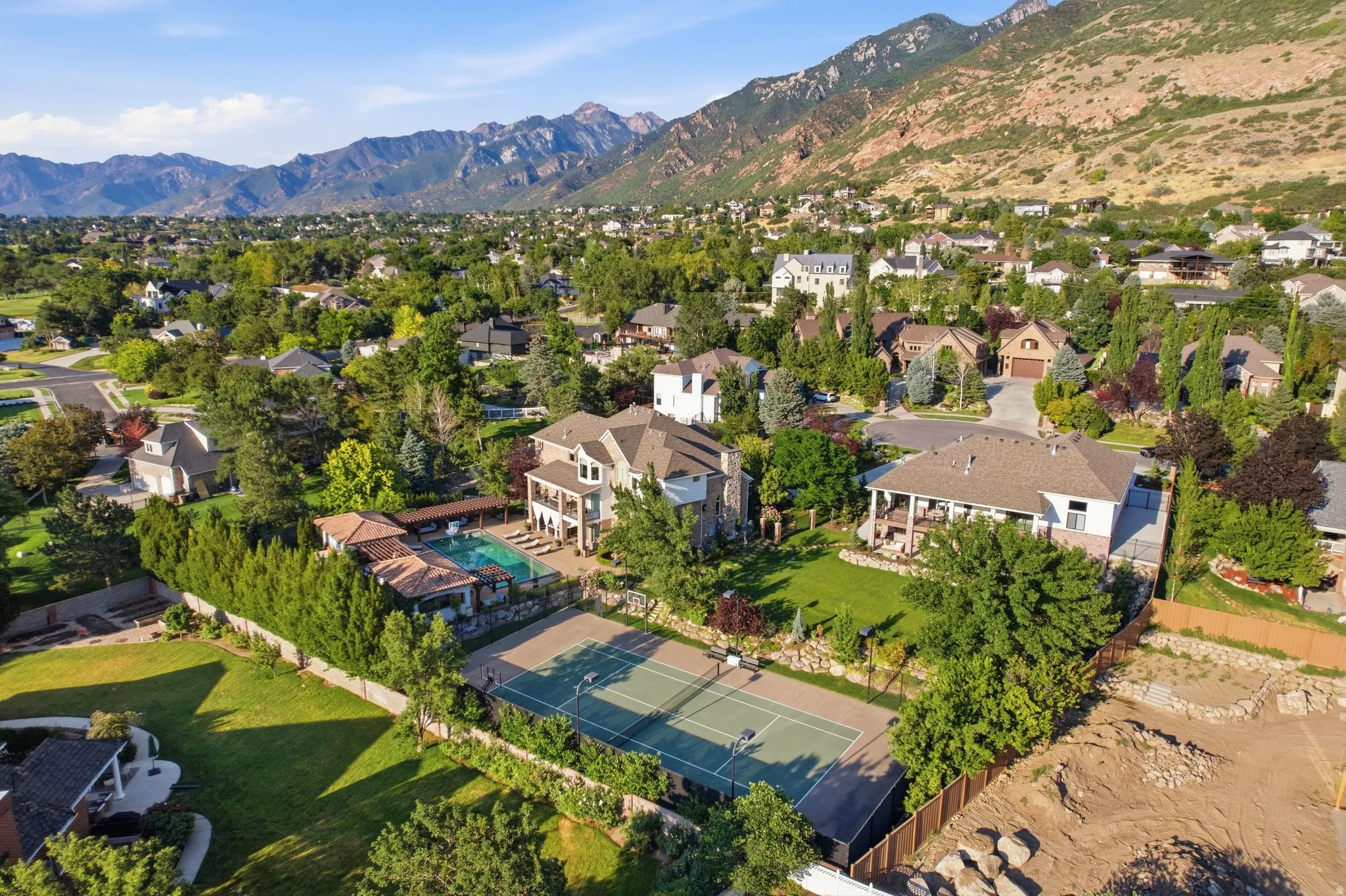 Expansive property featuring a multi-story residence, swimming pool, sports court, and mature landscaping