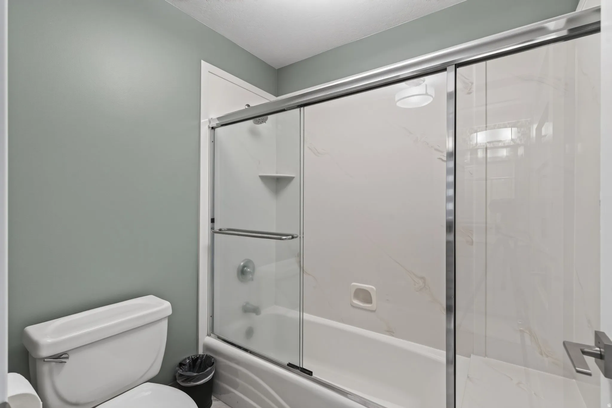 Tub and shower combination with sliding glass enclosure and white-patterned surround