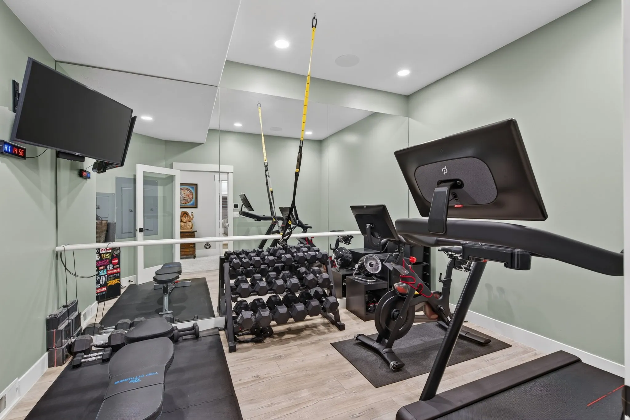 Recessed lighting, light-toned walls, wood-finish flooring, full-wall mirror, and a wall-mounted television