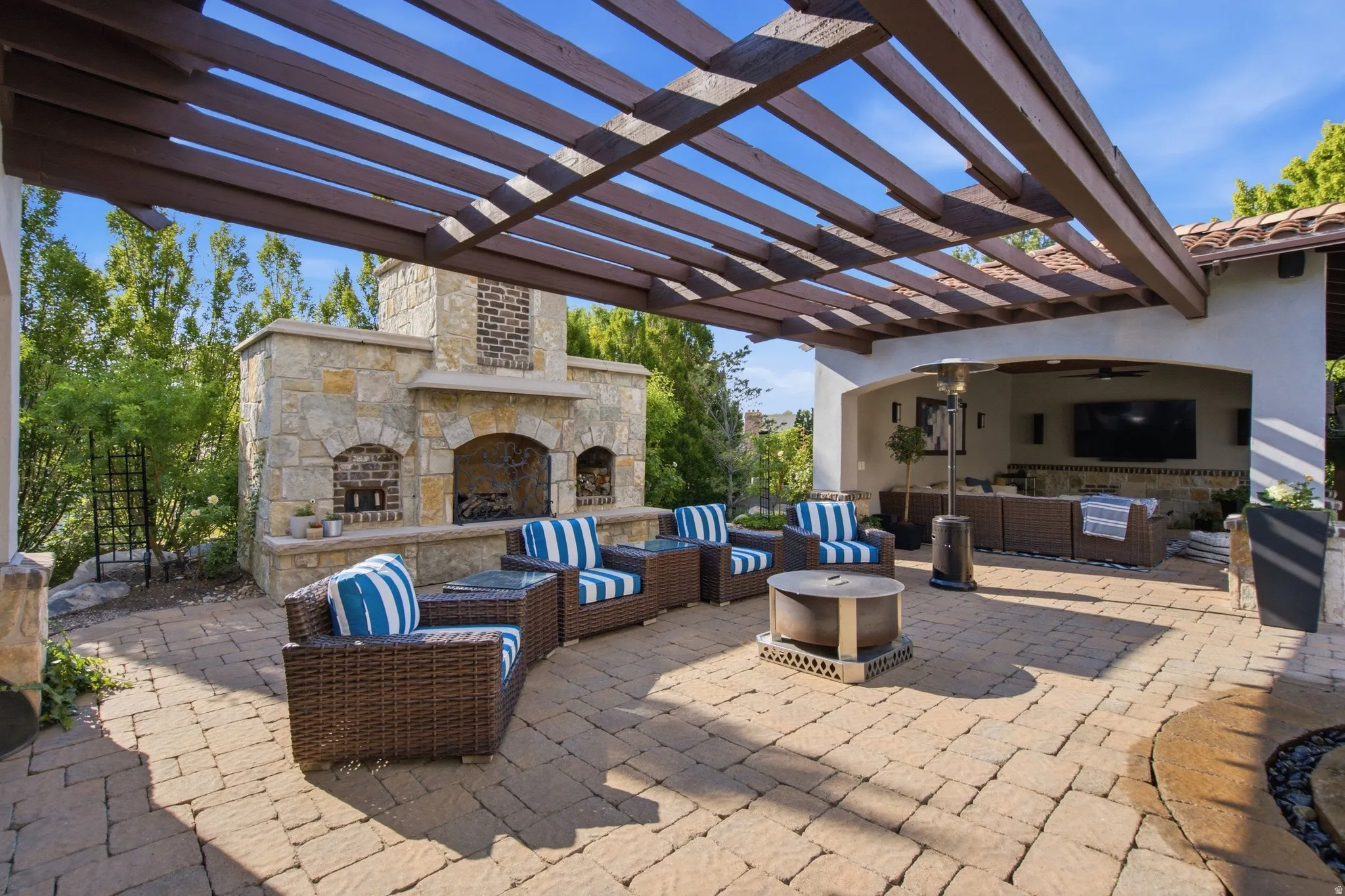 Paver patio featuring an outdoor stone fireplace, built-in entertainment area, and a wood pergola