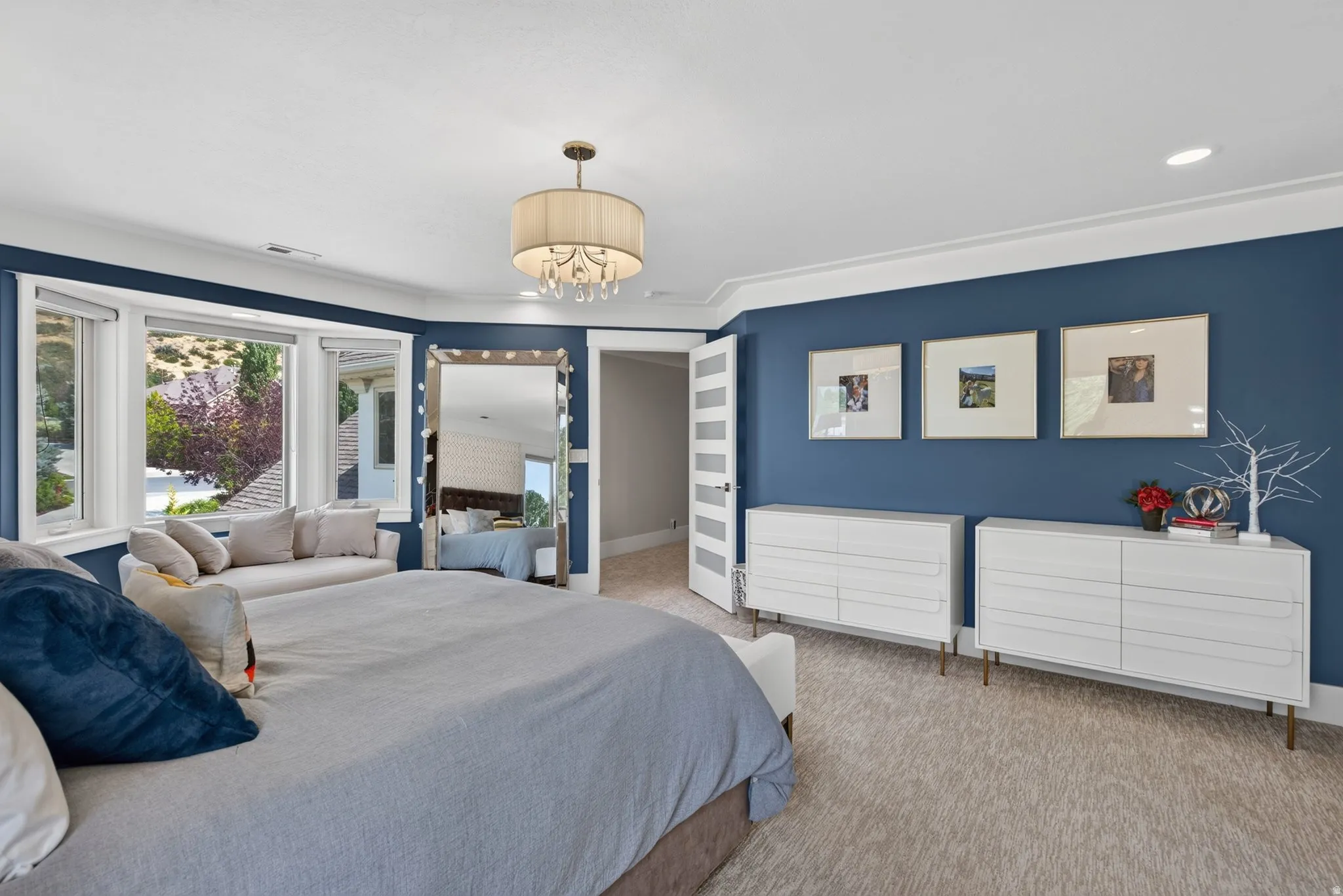 Carpeted room featuring a bay window, crown molding, and a drum-shade chandelier