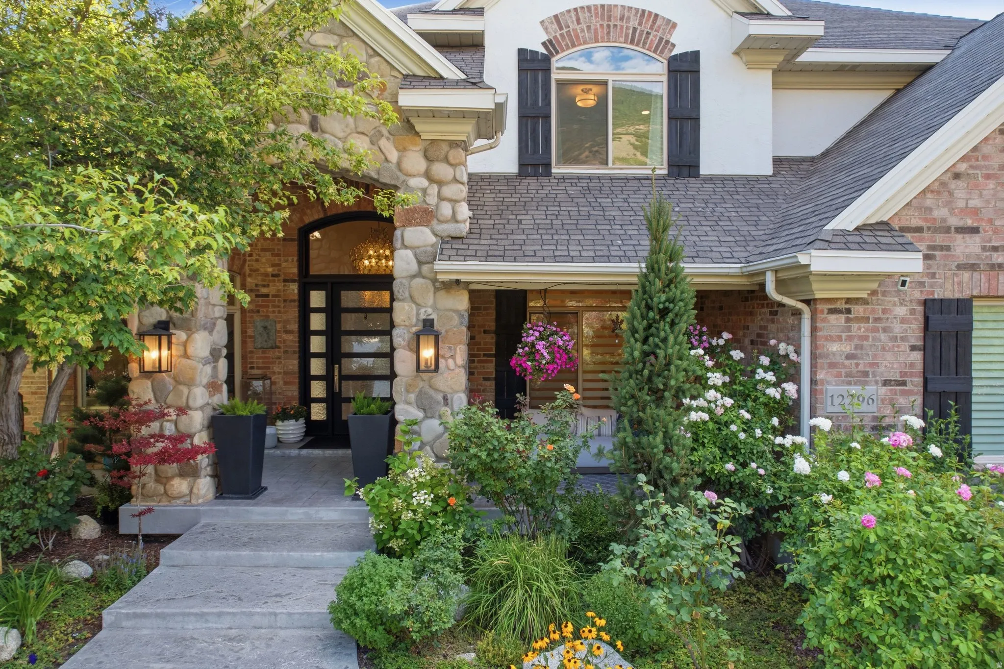 Stone and brick facade with an arched entryway, featuring a dark-framed front door with glass panels