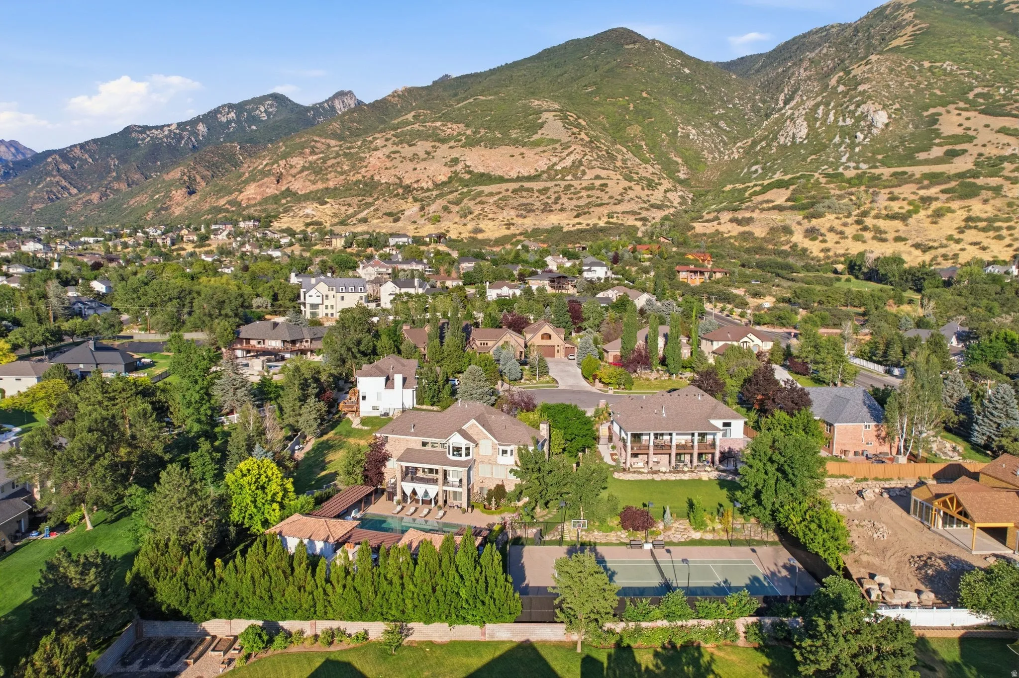 Expansive residential property featuring a full-size tennis court, swimming pool, and established landscaping