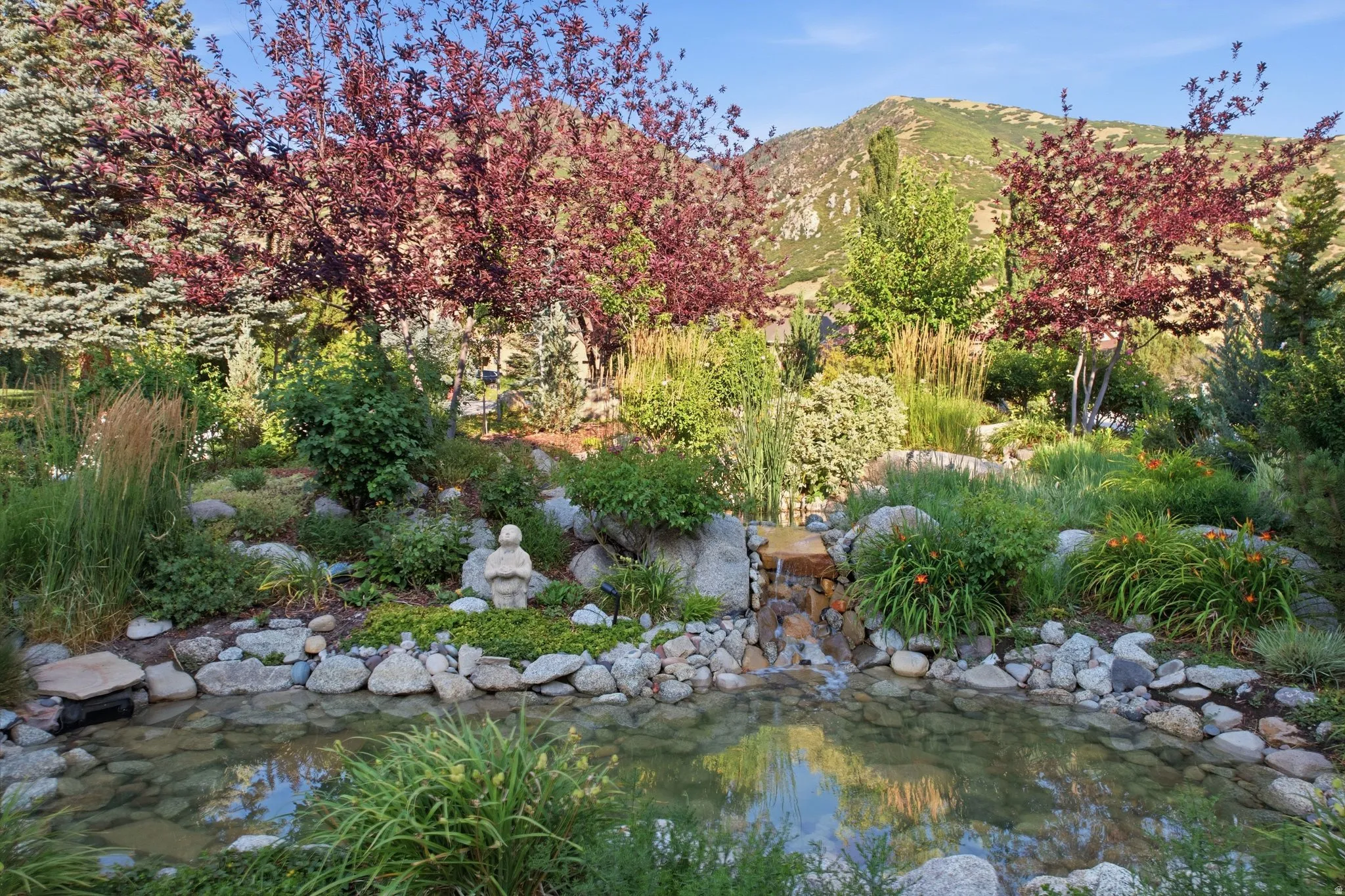 Landscaped grounds featuring a tranquil pond, rock accents, and a tiered waterfall feature