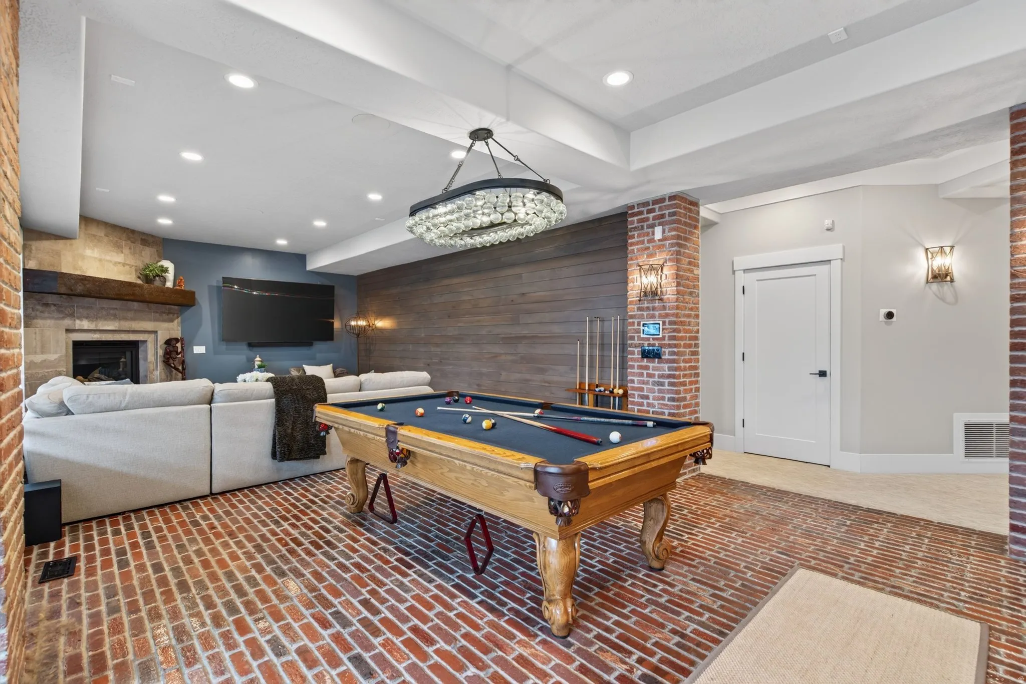 Exposed brick columns, wood-paneled accent wall, and recessed ceiling lighting
