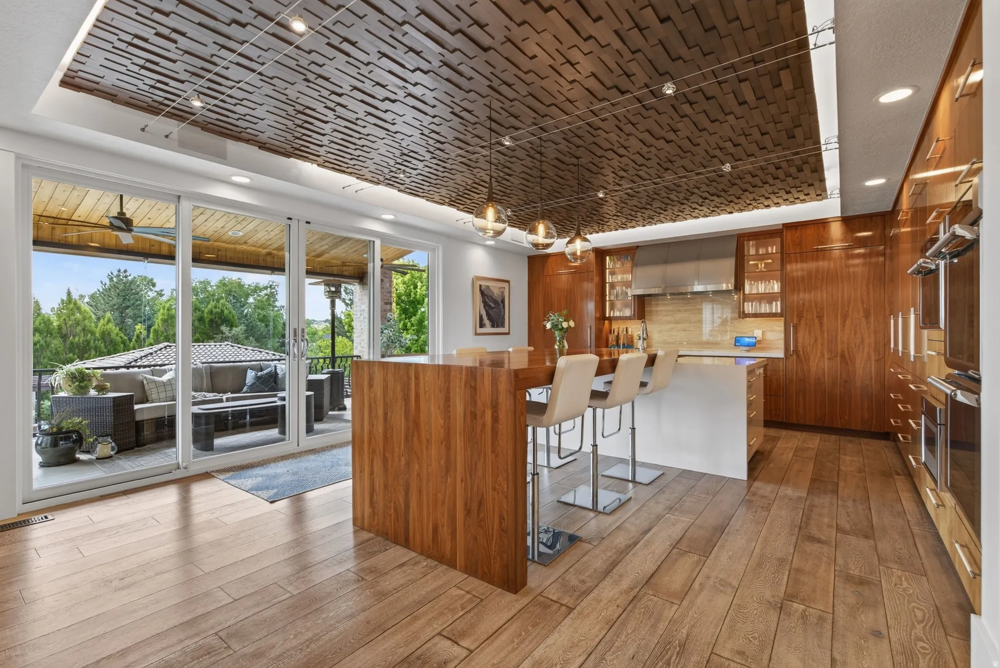Wood-finish flooring with a kitchen island featuring integrated seating and pendant lighting