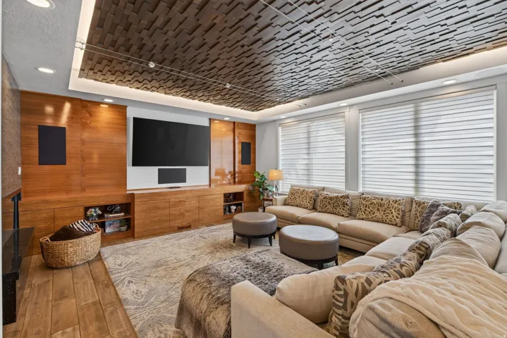Wood-finish flooring, custom wood-paneled media wall, recessed lighting, and a textured ceiling detail