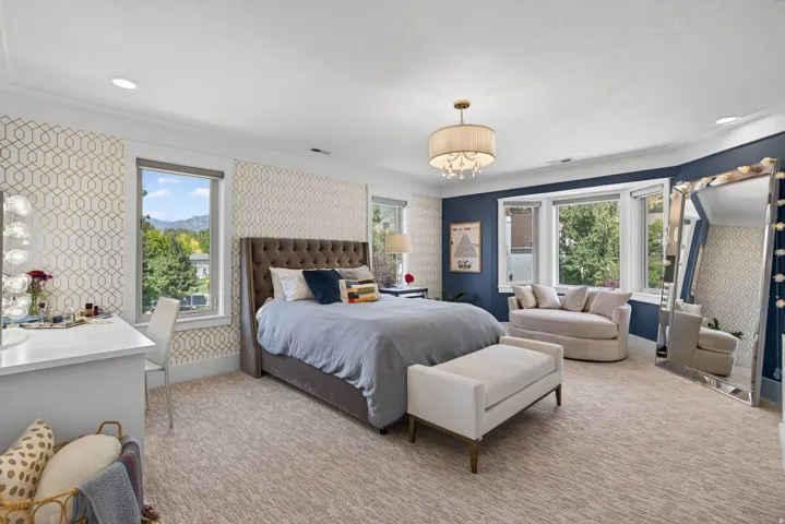 Recessed lighting, patterned accent walls, tray ceiling, drum chandelier, and a bay window