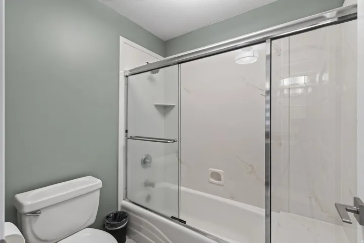 Tub and shower combination with sliding glass enclosure and white-patterned surround