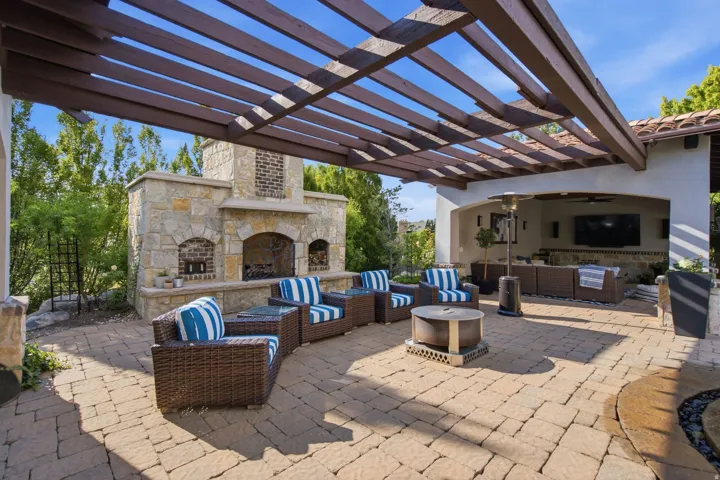 Paver patio featuring an outdoor stone fireplace, built-in entertainment area, and a wood pergola
