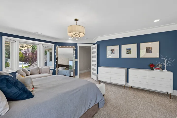 Carpeted room featuring a bay window, crown molding, and a drum-shade chandelier
