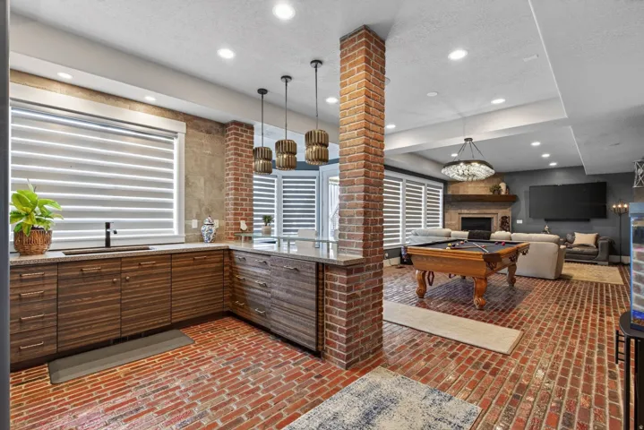 Brick flooring, exposed brick structural elements, wood-finish cabinetry, built-in sink, and recessed lighting