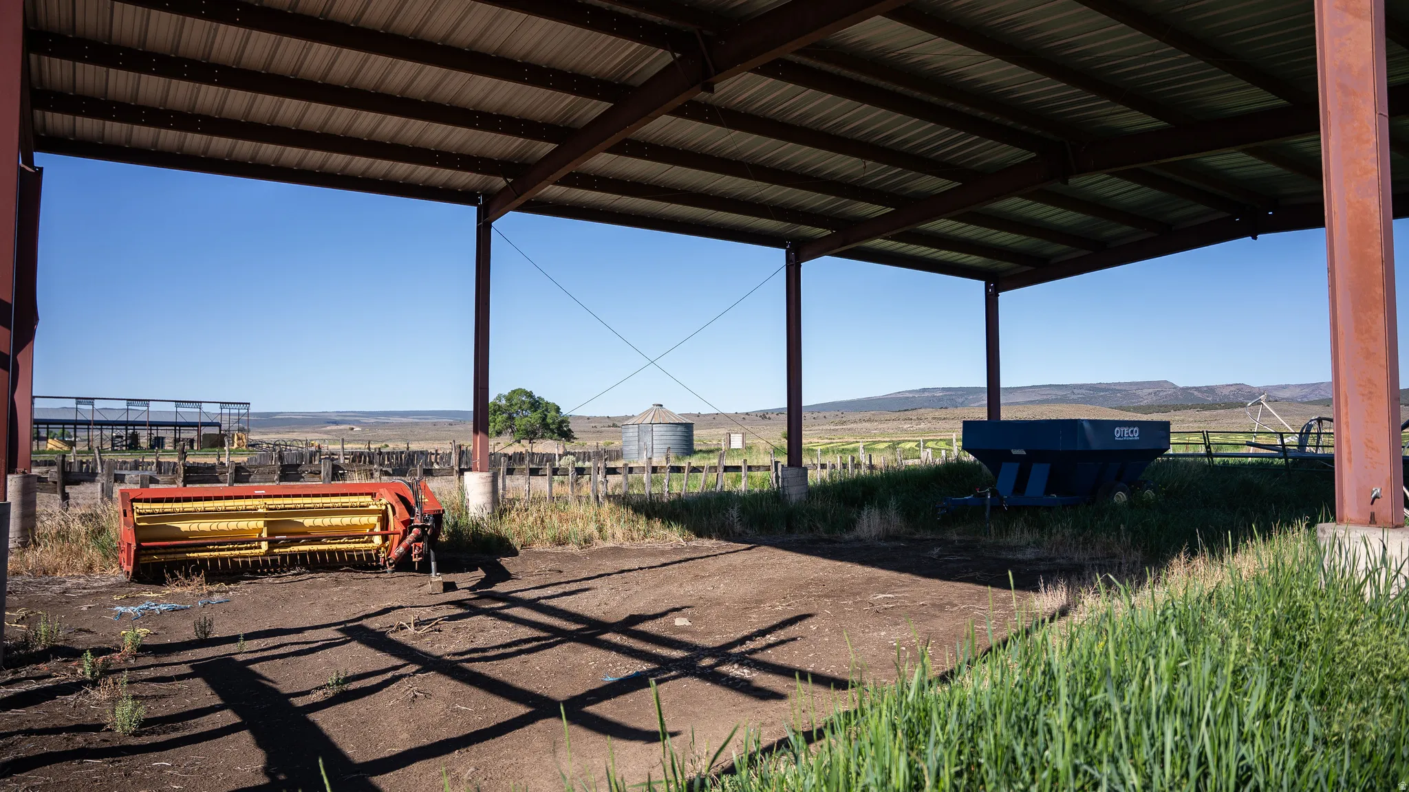 Open-sided metal structure with a corrugated roof, supported by robust metal columns