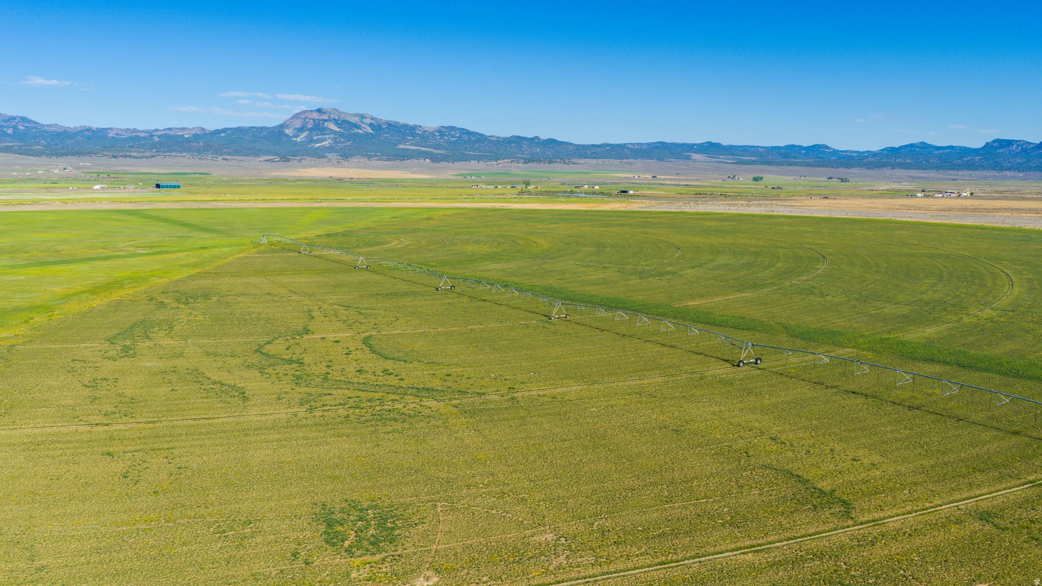 Expansive agricultural land featuring a center pivot irrigation system and distant mountain ranges
