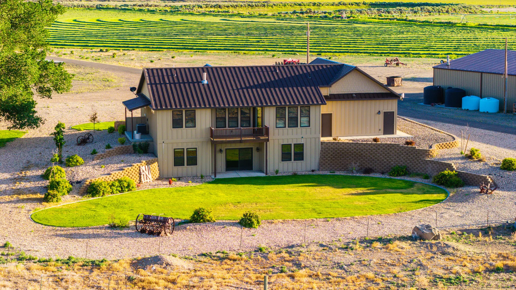 Two-story residence with a metal roof, an upper-level balcony, and a ground-level patio
