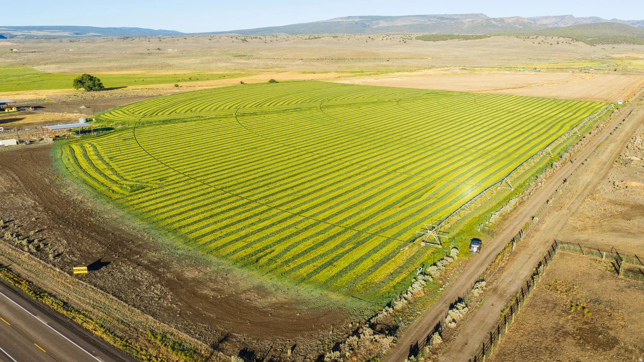 Expansive agricultural land featuring a center pivot irrigation system, cultivated fields, and surrounding rural terrain
