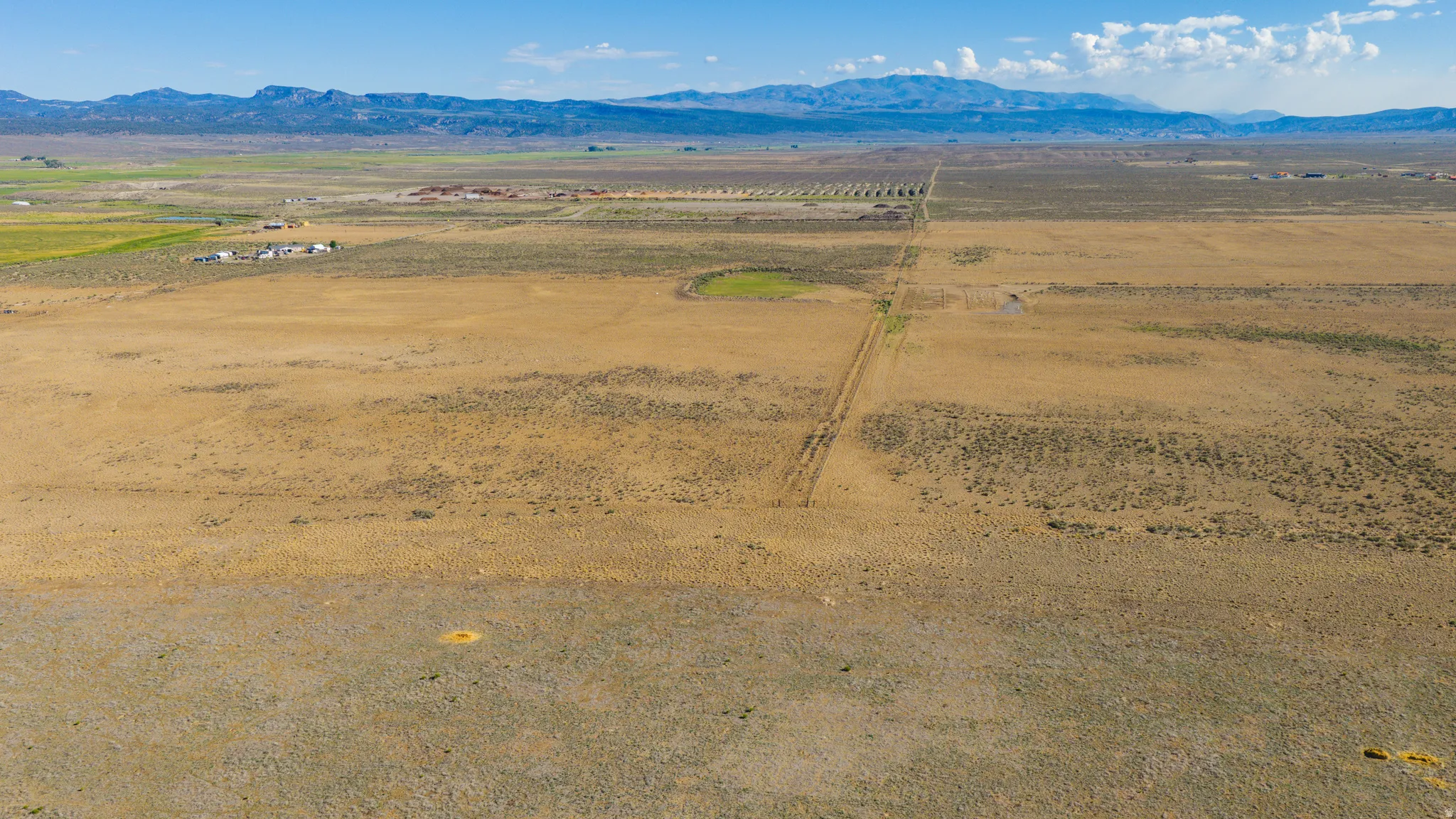 Expansive undeveloped land featuring diverse vegetation and distant mountain ranges
