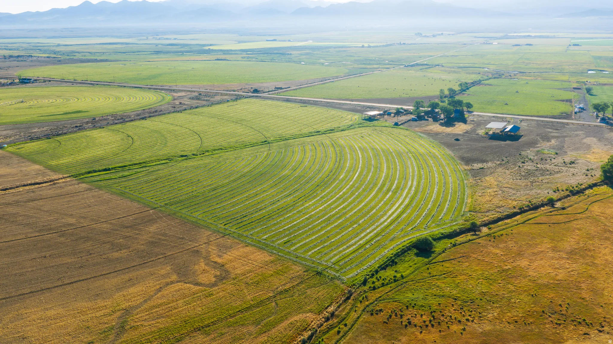 Expansive agricultural land featuring cultivated fields, irrigation patterns, and distant mountains