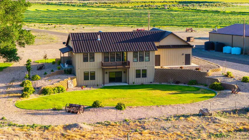 Two-story residence with a metal roof, an upper-level balcony, and a ground-level patio