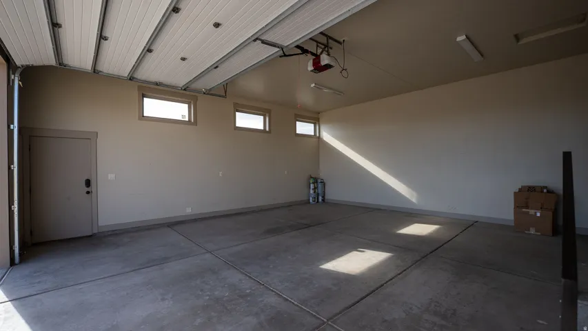 Spacious garage with a concrete floor, overhead lighting, and an automatic garage door opener