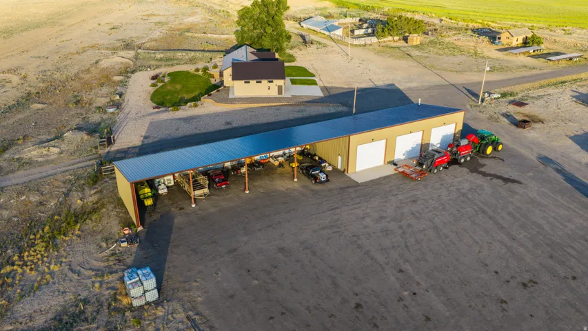 Large metal building with multiple garage doors, an extended covered awning, and an expansive gravel lot