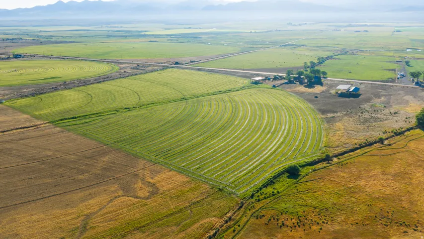 Expansive agricultural land featuring cultivated fields, irrigation patterns, and distant mountains