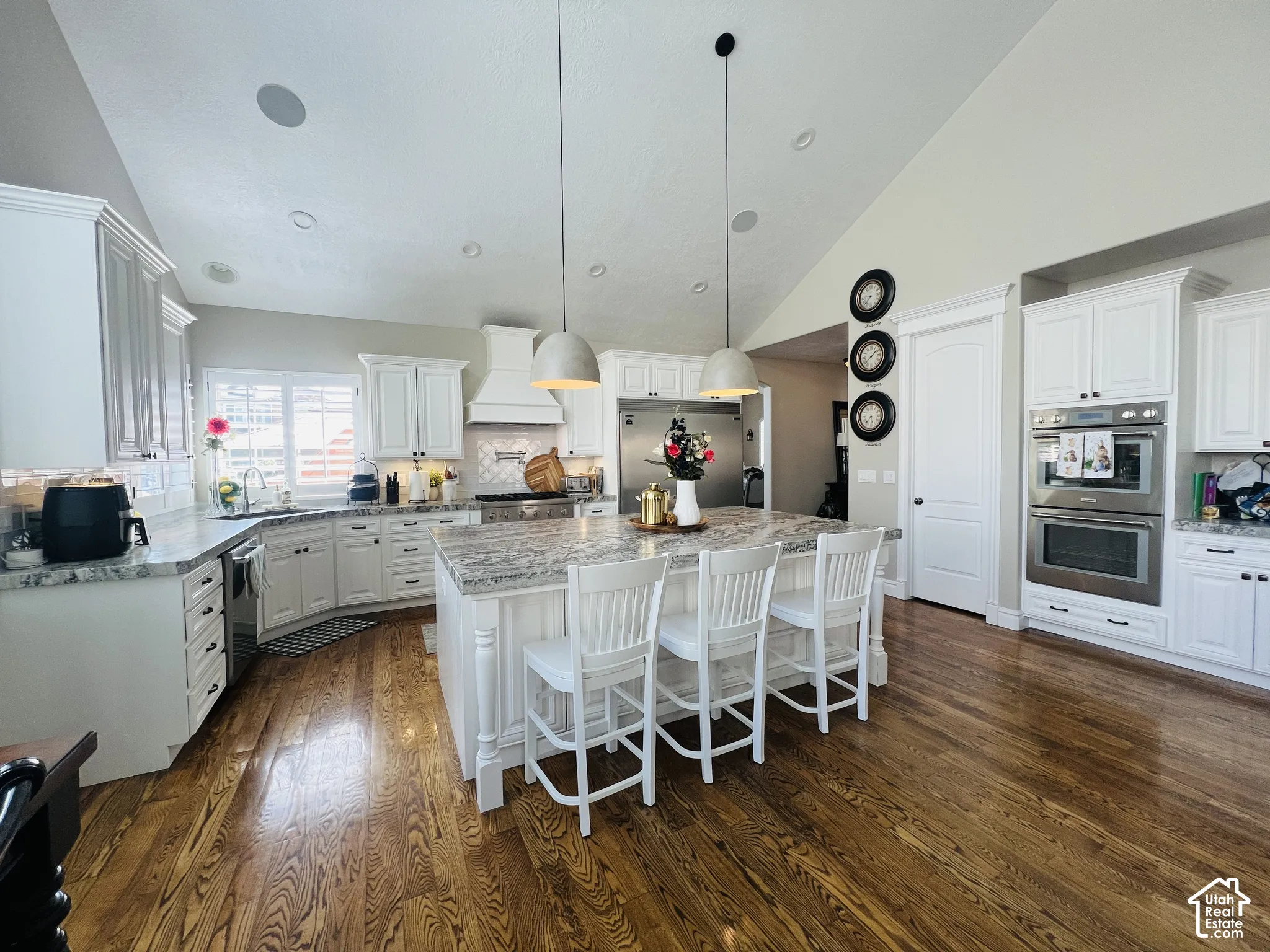 Kitchen featuring hardwood flooring, white cabinetry, granite countertops, a built-in double oven, and an island with pendant lighting