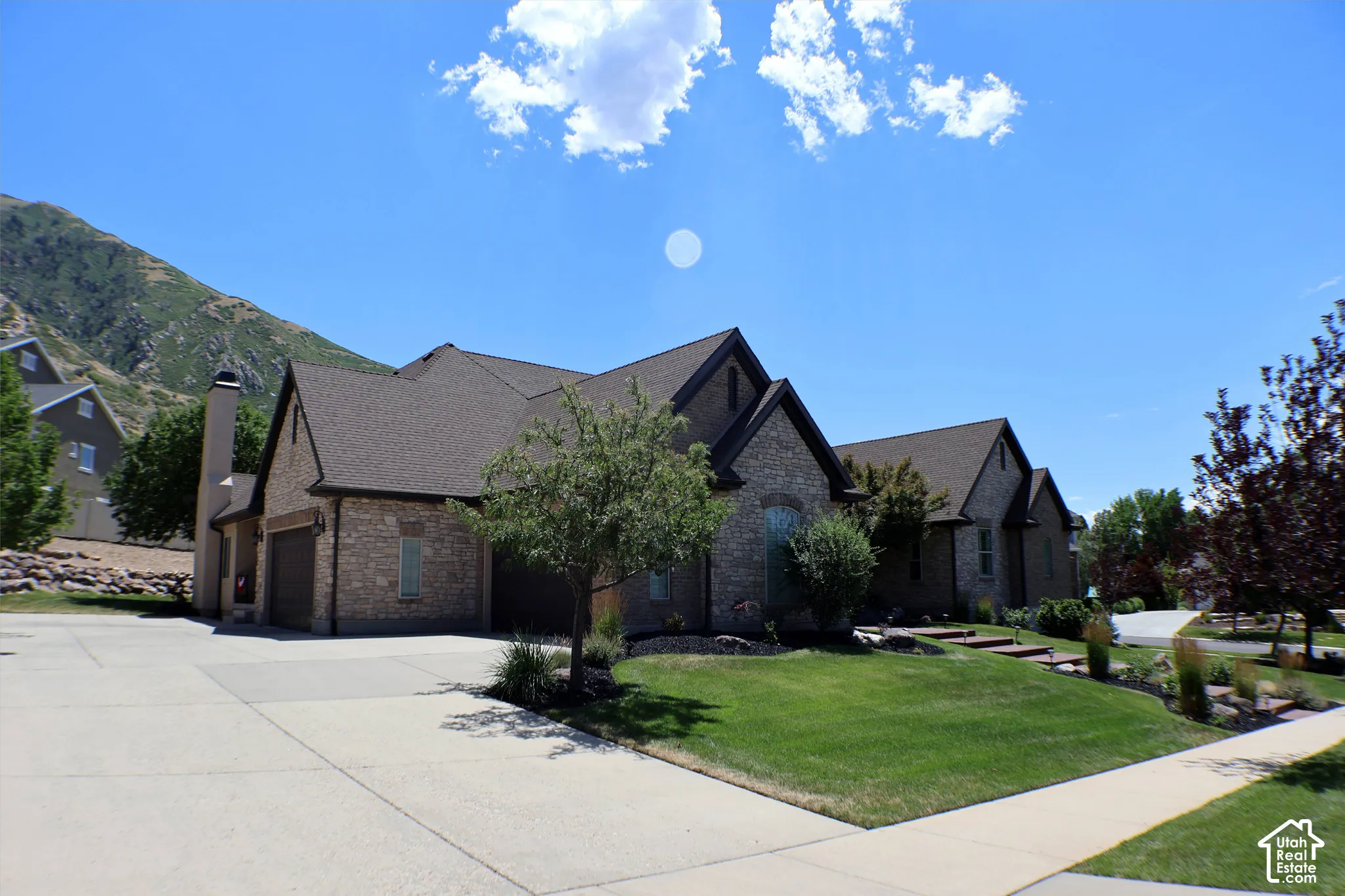 Stone and stucco exterior with dark brown gables, attached two-car garage, and a concrete driveway