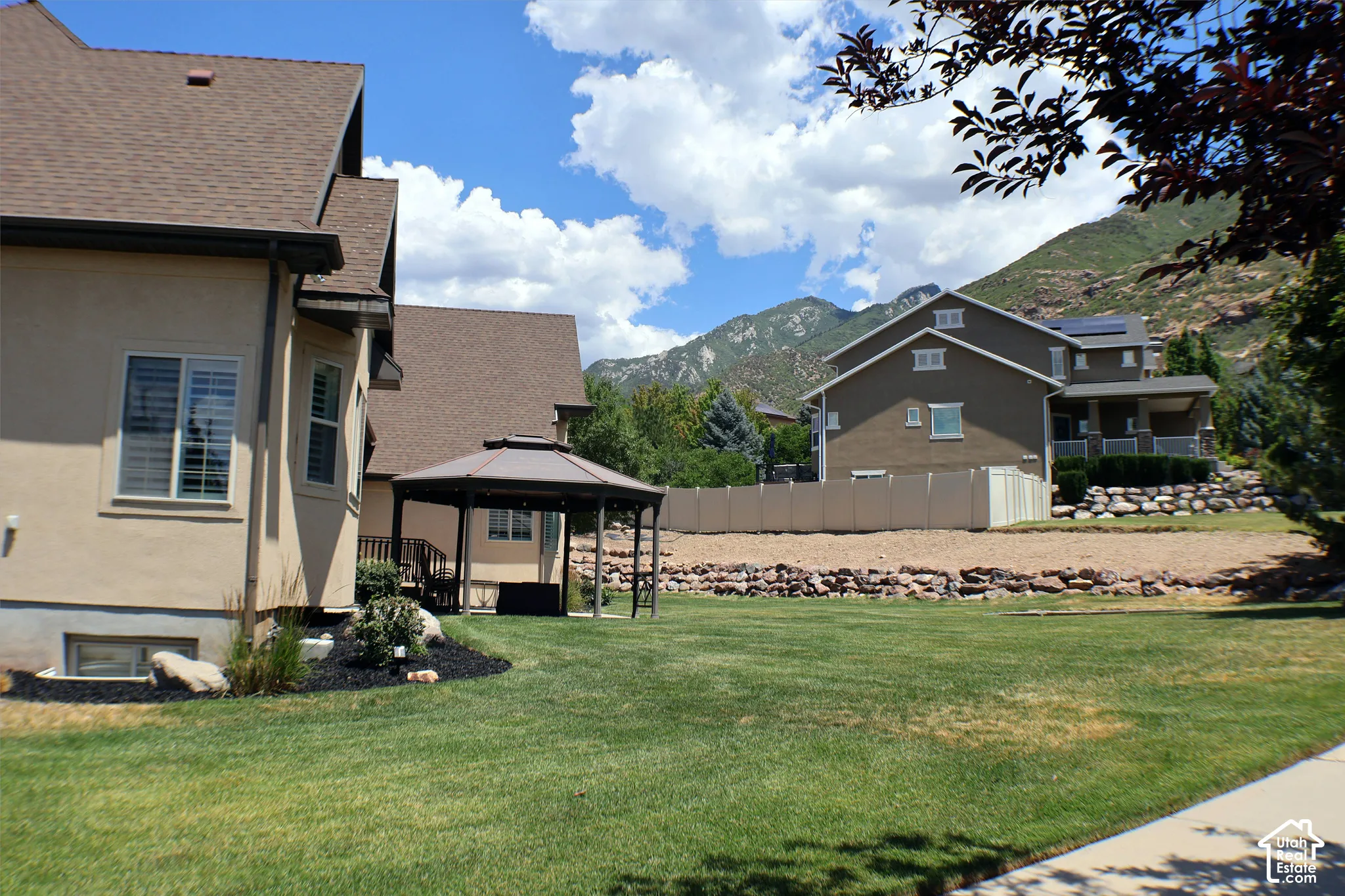 Expansive lawn with a built-in gazebo, stucco exterior, and mountain backdrop