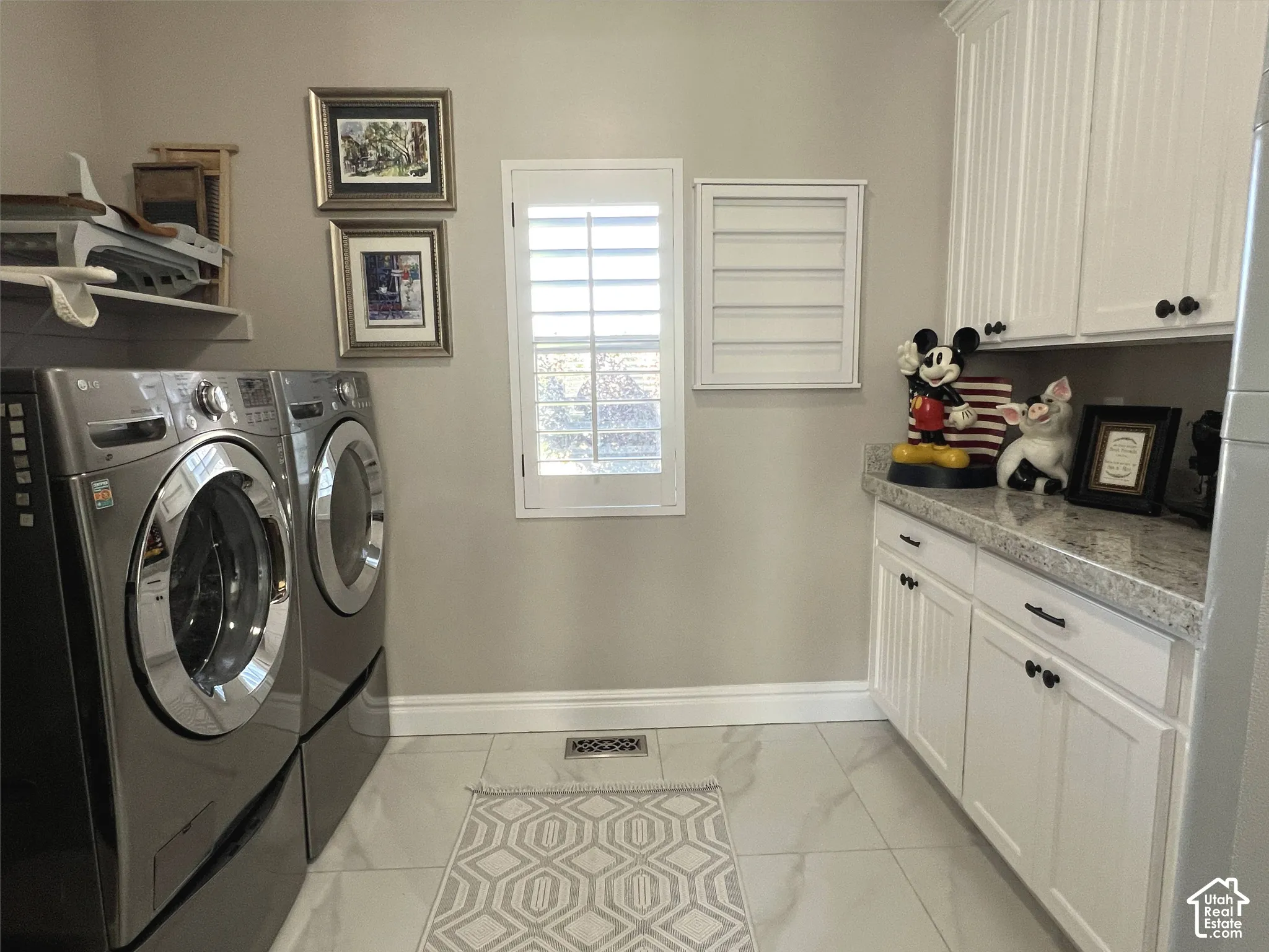 Laundry area featuring white cabinetry, a light-toned countertop, and light-colored tile flooring
