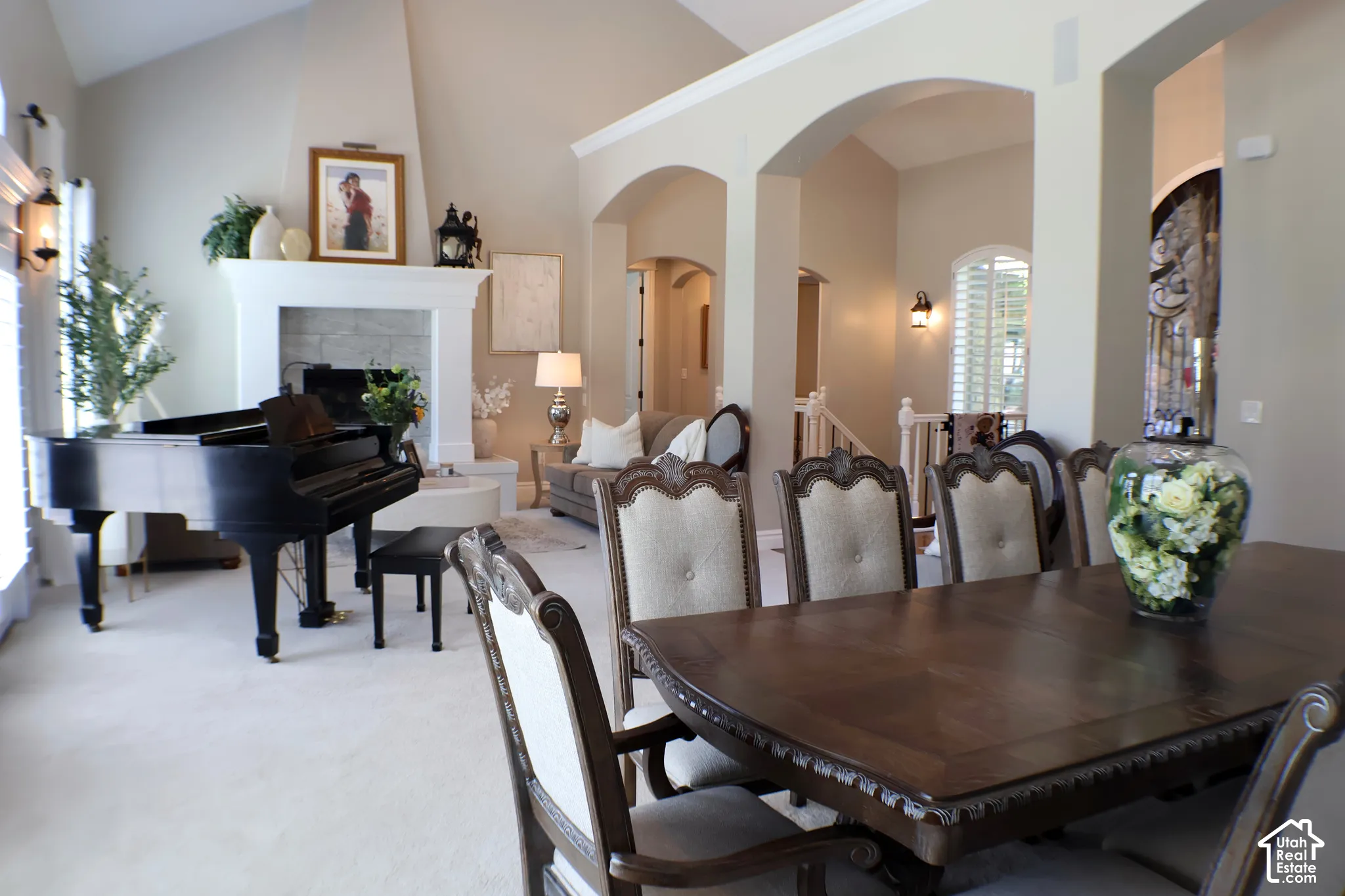 Vaulted ceilings with crown molding, arched entryways, and a stone-faced fireplace with a substantial mantel