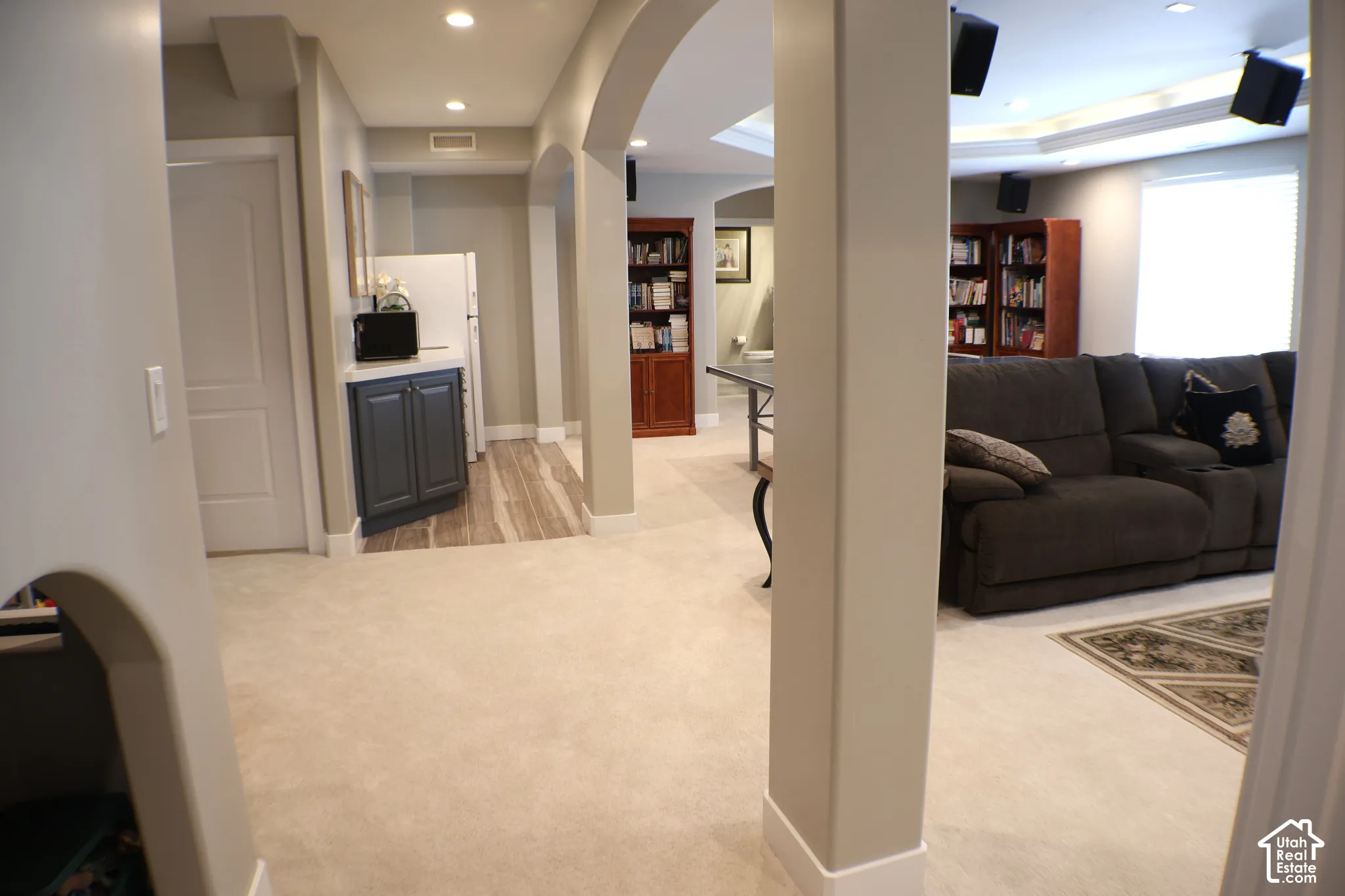 Recessed lighting, arched doorways, built-in shelving, tray ceiling, and a built-in cabinet