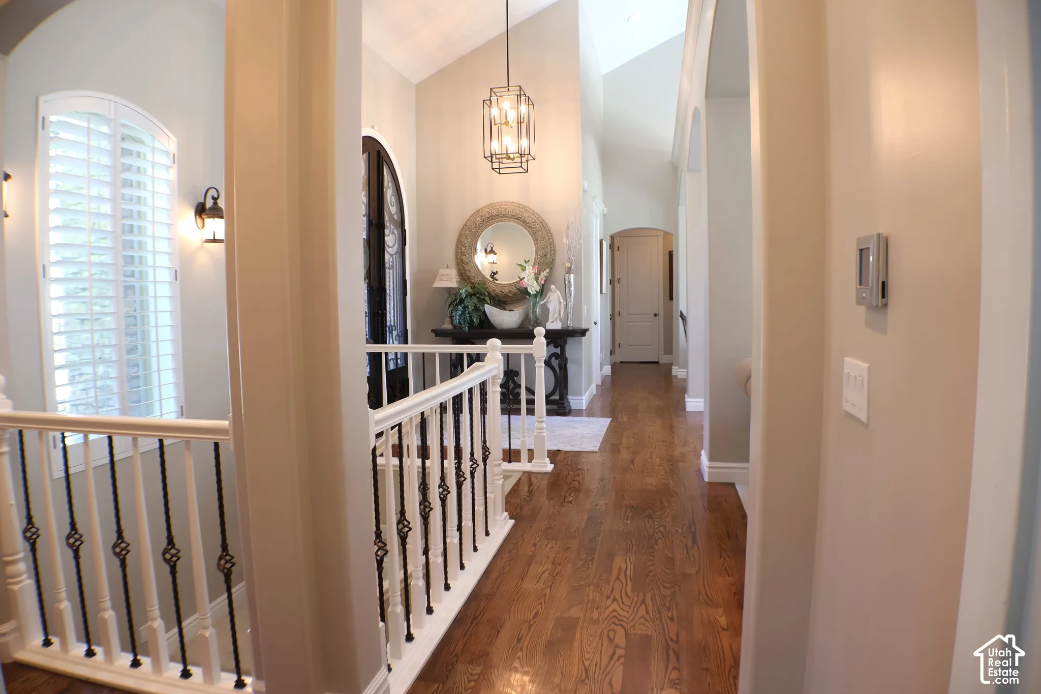 Hardwood flooring, arched doorways, vaulted ceilings, plantation shutters, and an open-concept hallway