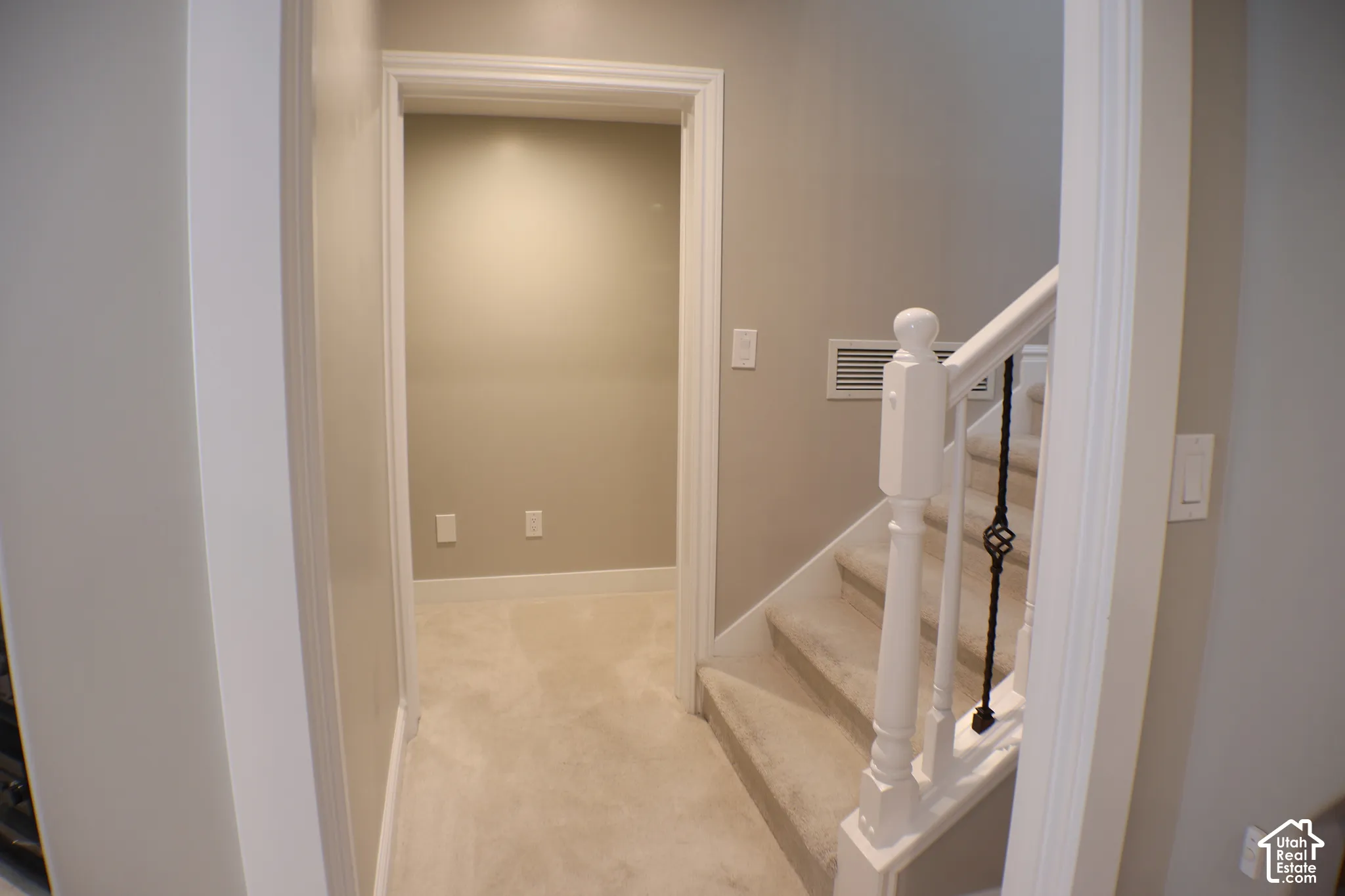 Carpeted staircase with white balusters and wrought iron spindles