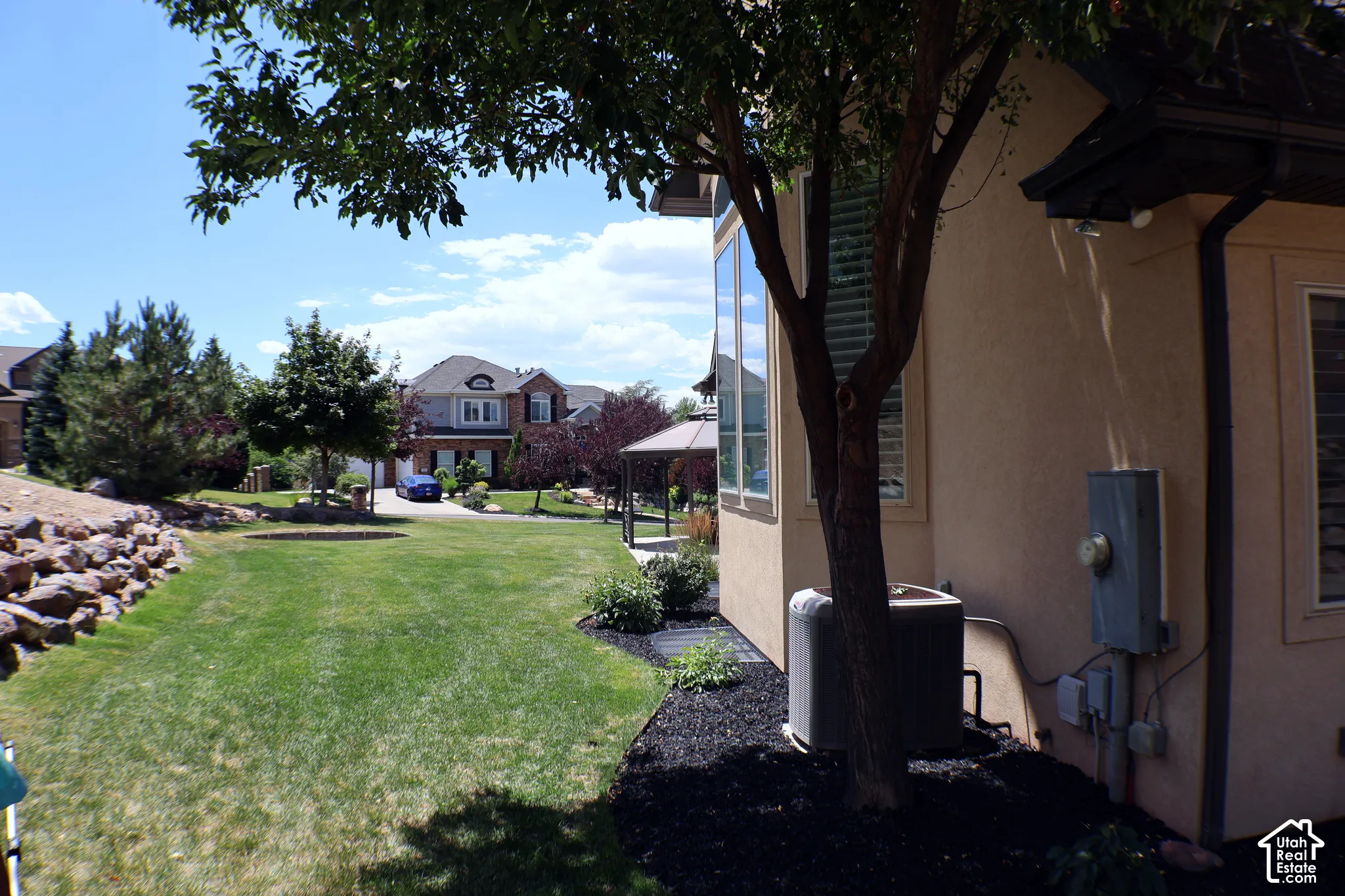 Expansive lawn area with a rock retaining wall and mature trees