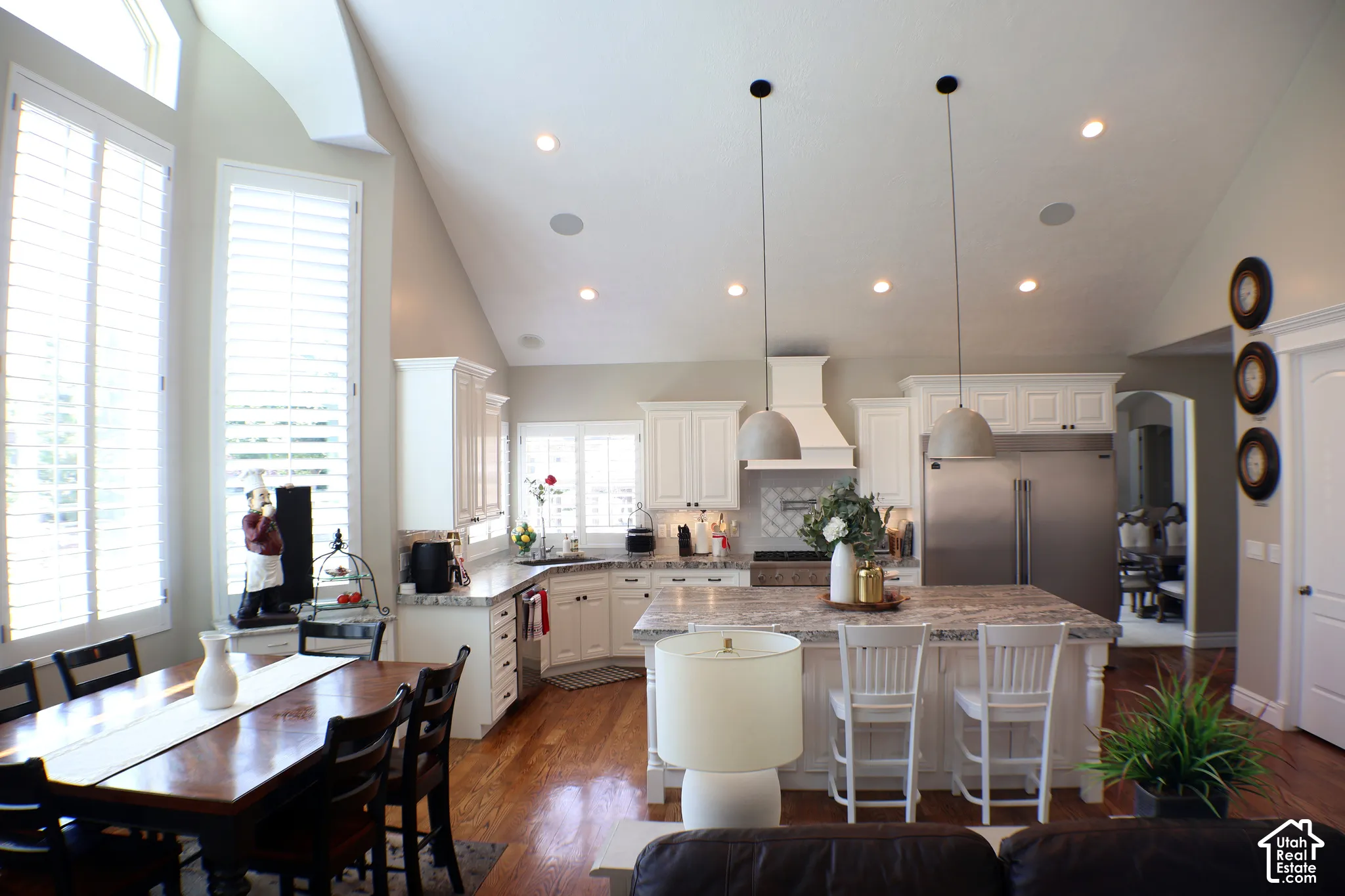 Spacious kitchen featuring white cabinetry, a large center island with seating, stainless steel appliances, and recessed lighting