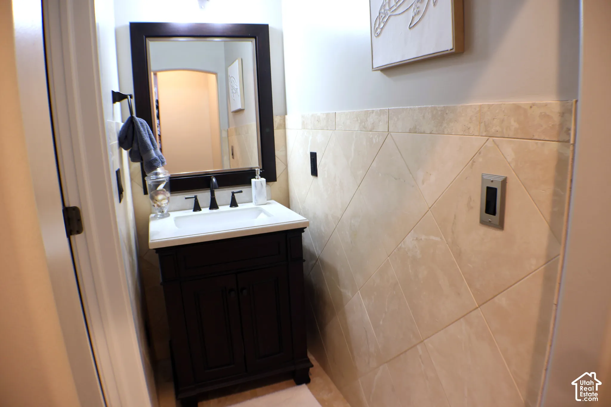 Dark wood vanity with a white rectangular sink, matte black faucet, and framed mirror
