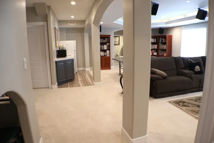 Recessed lighting, arched doorways, built-in shelving, tray ceiling, and a built-in cabinet
