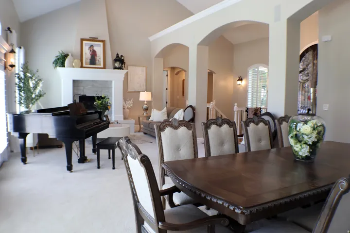 Vaulted ceilings with crown molding, arched entryways, and a stone-faced fireplace with a substantial mantel