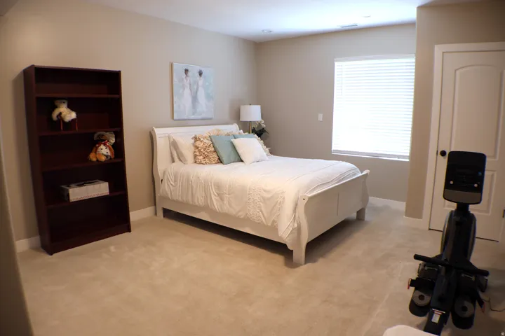 Recessed ceiling lighting, light-colored carpeting, window with blinds, light-toned wall paint, and a classic-style interior door