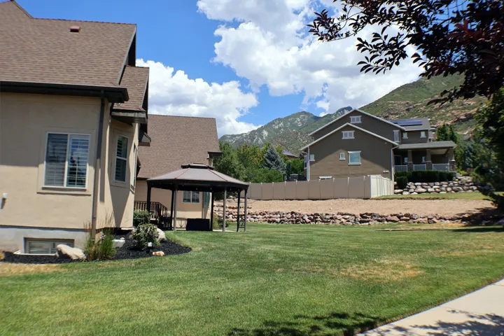 Expansive lawn with a built-in gazebo, stucco exterior, and mountain backdrop