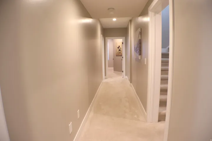 Hallway featuring recessed lighting, light-toned carpeting, and a staircase with carpeted treads