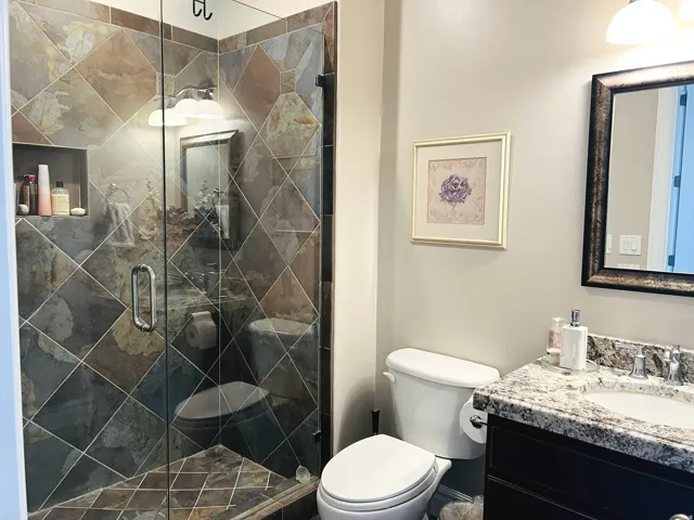 Glass-enclosed shower with diagonal tilework and a built-in shower niche