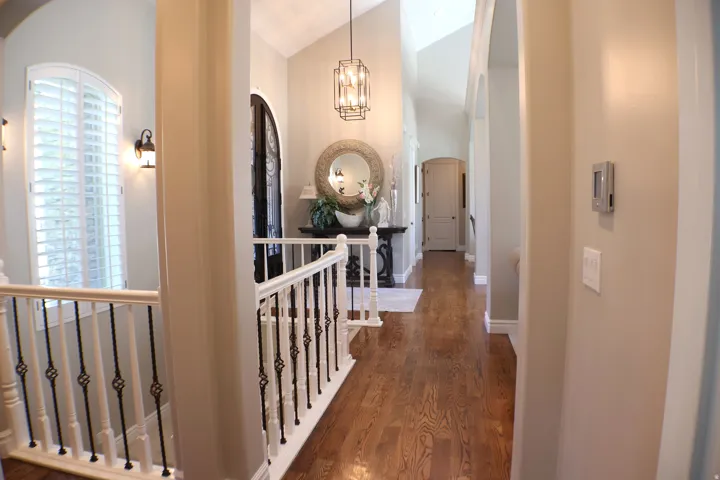 Hardwood flooring, arched doorways, vaulted ceilings, plantation shutters, and an open-concept hallway
