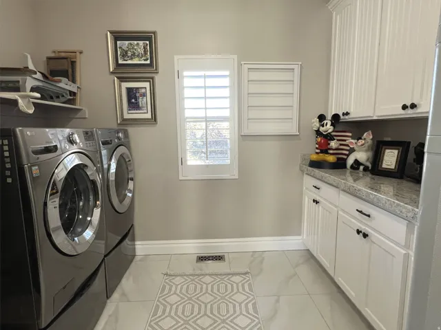 Laundry area featuring white cabinetry, a light-toned countertop, and light-colored tile flooring