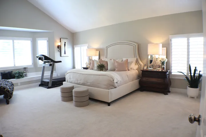 Vaulted ceiling room with window seating, plantation shutters, and light-toned carpeting