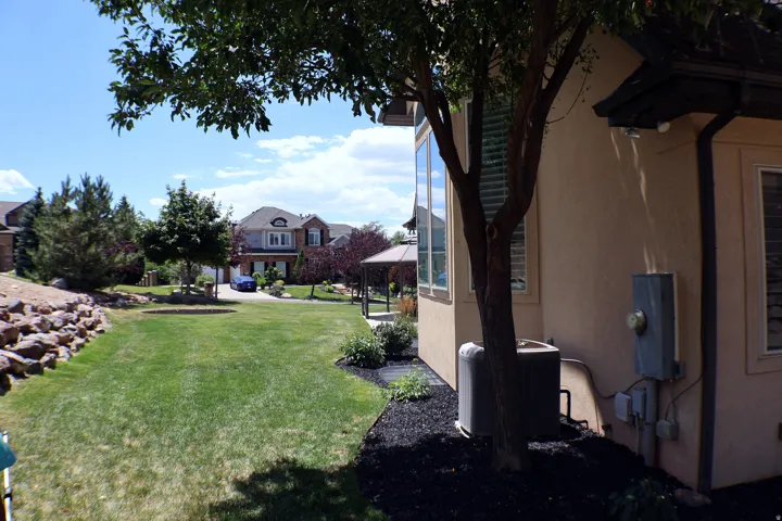 Expansive lawn area with a rock retaining wall and mature trees